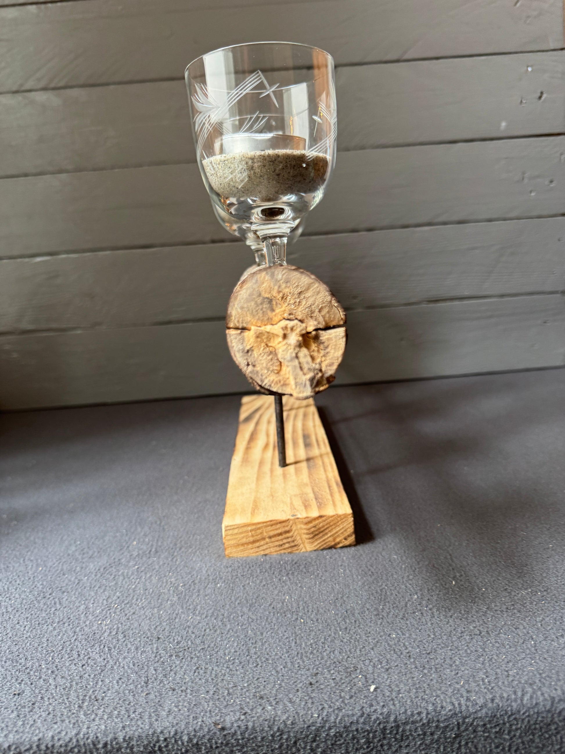 Detailaufnahme eines alten Weinglases als Teelichthalter auf Treibholz-Adventsgesteck