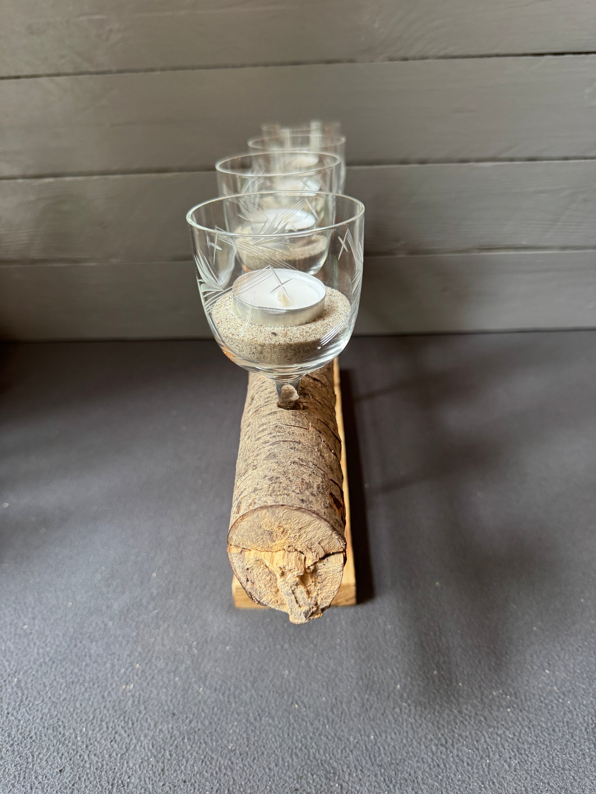 Nahaufnahme der Teelichter in den alten Weingläsern auf dem Treibholz-Adventsgesteck