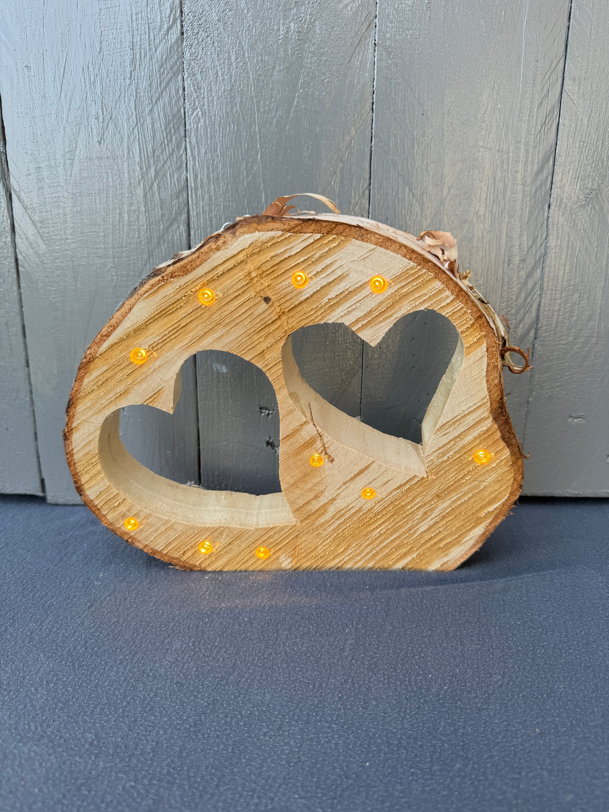 Baumscheibe mit zwei eingesägten Herzen und integrierter LED-Lichterkette, handgefertigt aus regionalem Naturholz – romantische Dekoration & Geschenkidee mit Licht.