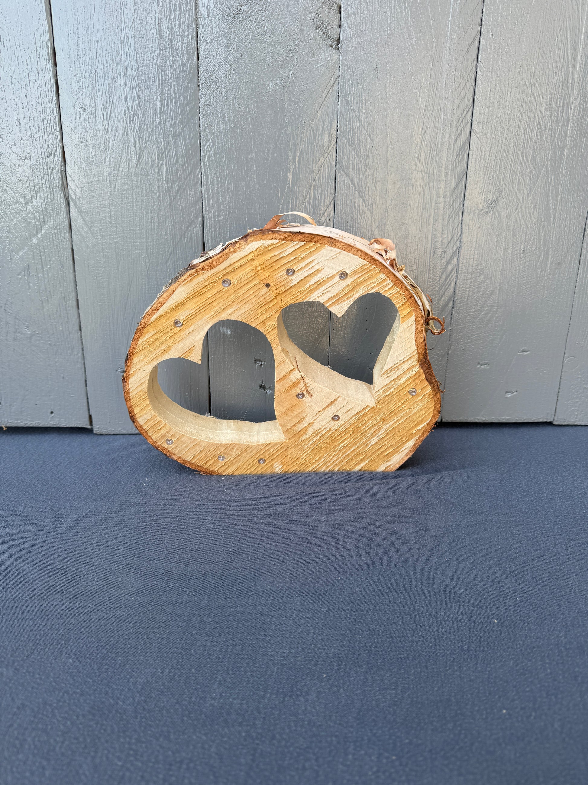 Baumscheibe mit zwei eingesägten Herzen und integrierter LED-Lichterkette, handgefertigt aus regionalem Naturholz – romantische Dekoration & Geschenkidee mit Licht.