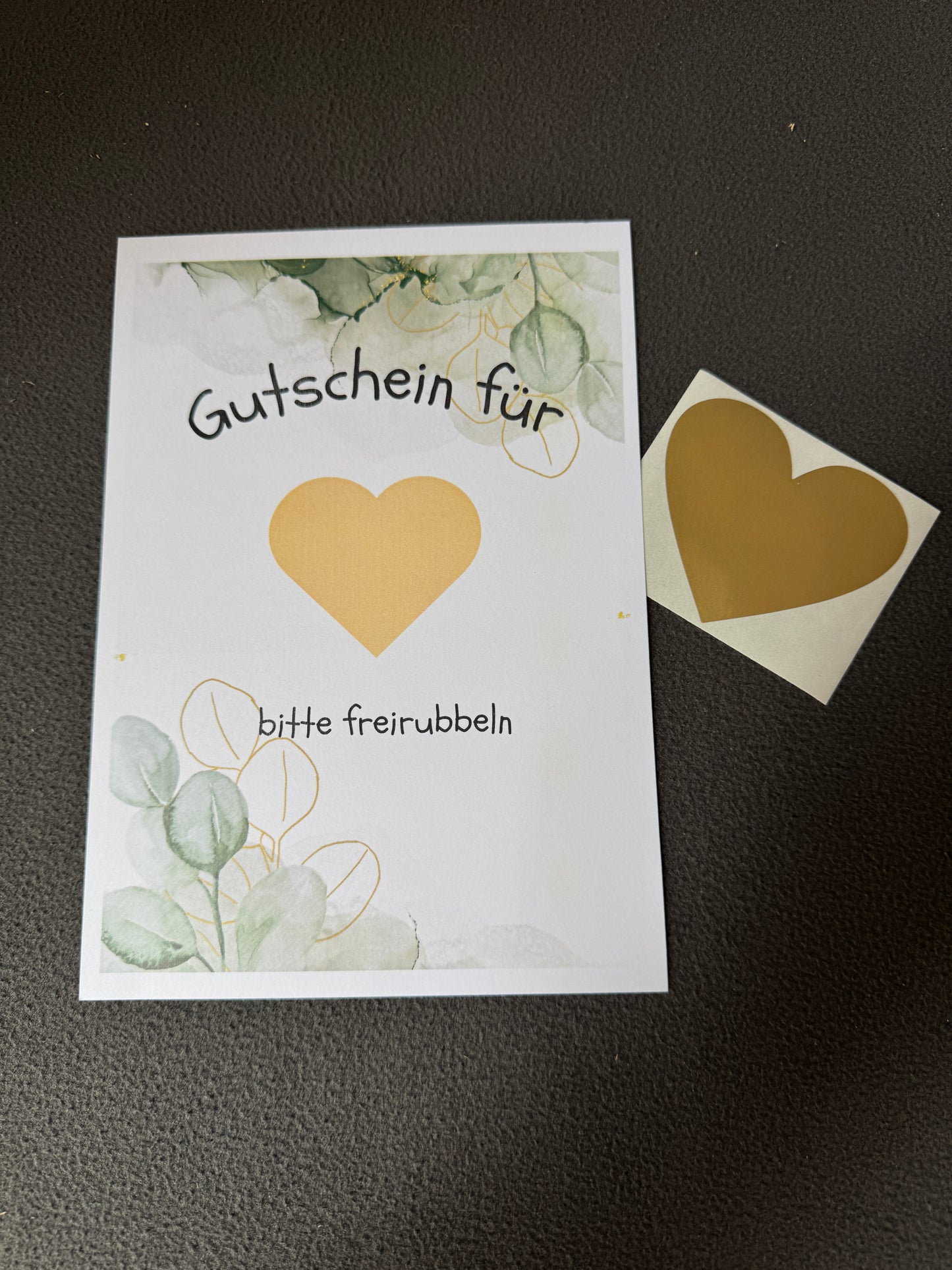 Rubbellos „Gutschein“ mit Eukalyptus-Motiv und goldenem Rubbelherz für persönliche Botschaften.