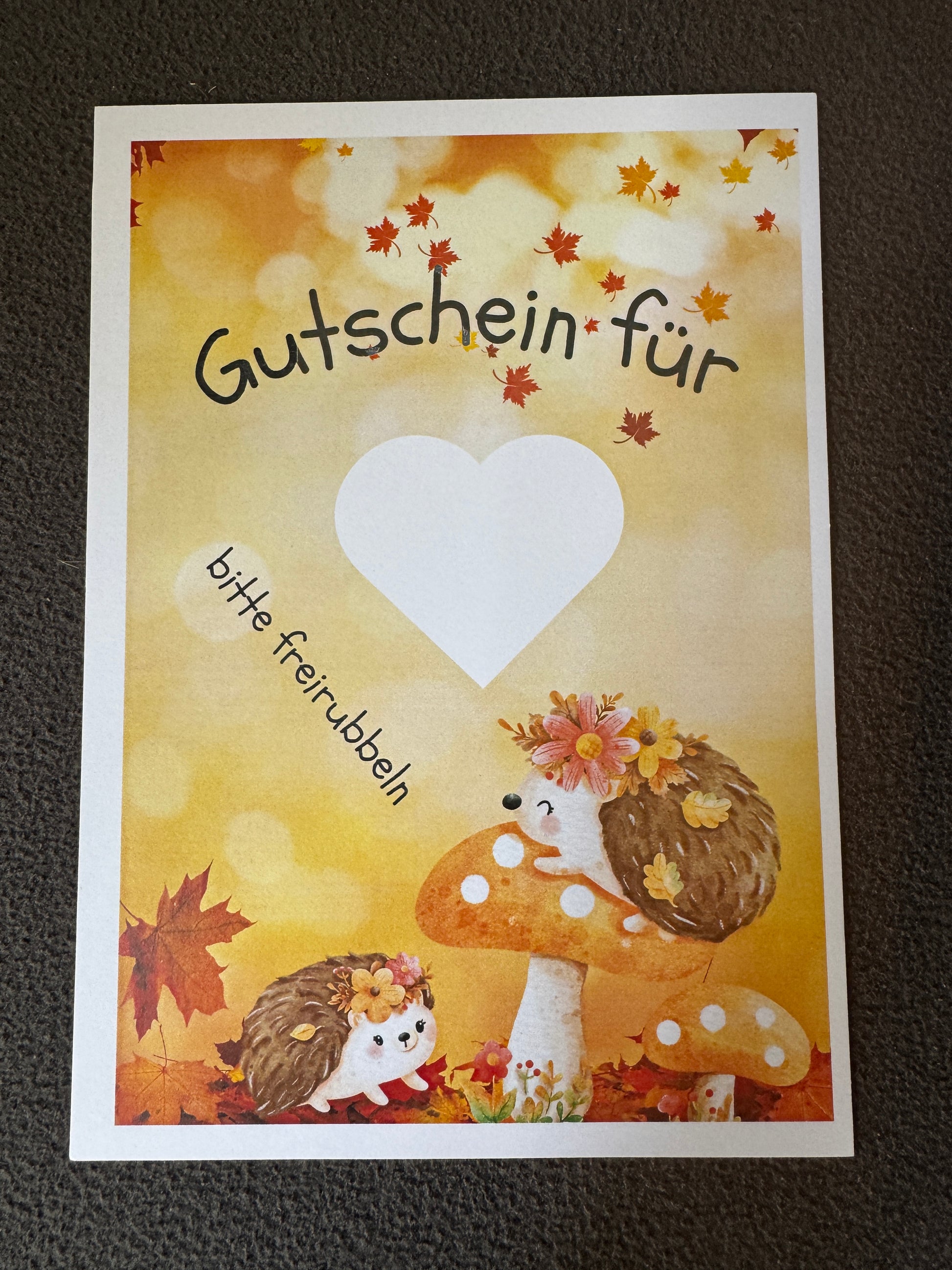 Rubbellos „Gutschein“ für den Herbst mit warmen Blattmotiven und Igel auf hochwertigem Papier.