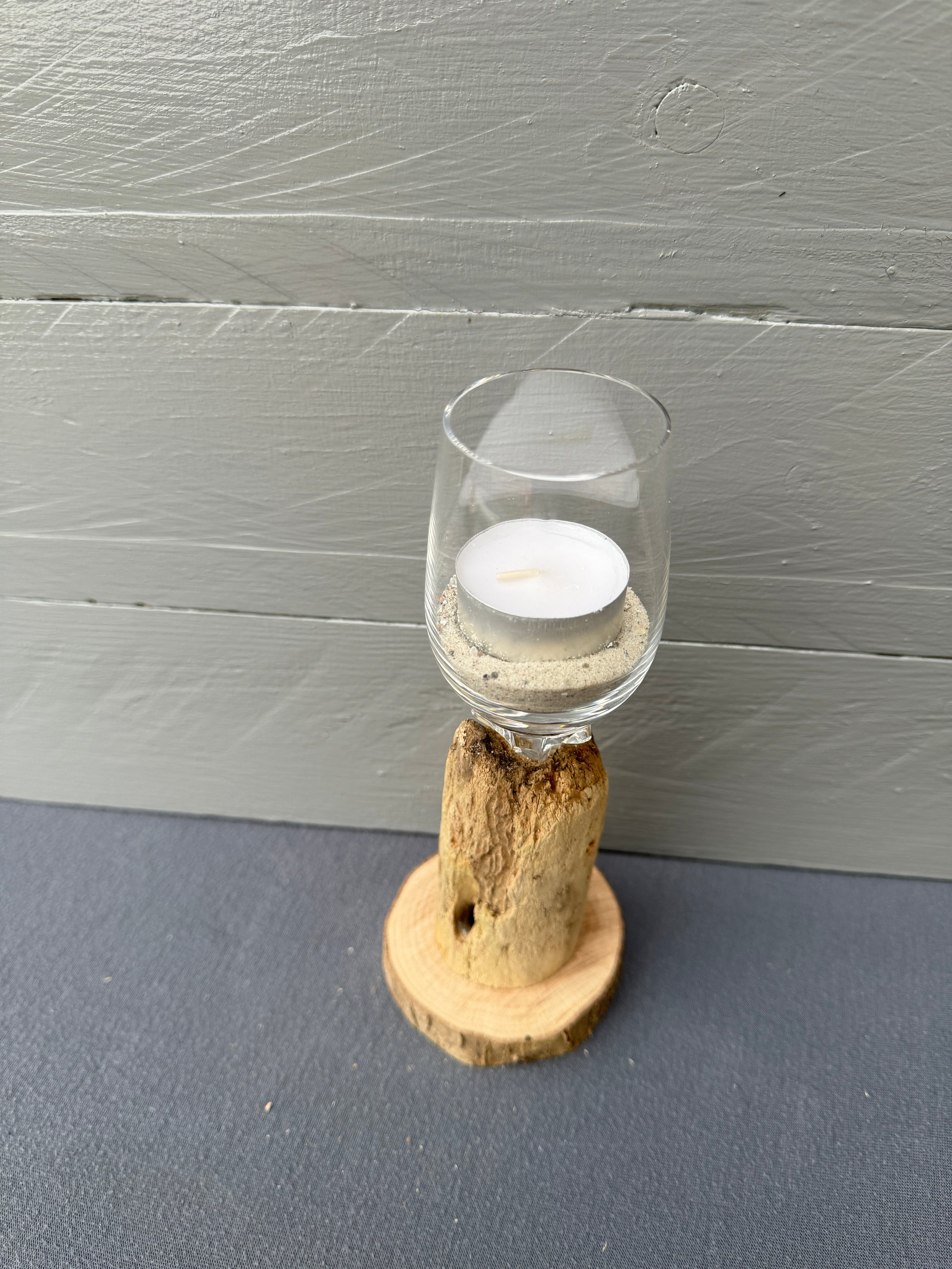 Nahaufnahme des Schnapsglases mit Ostseesand und Teelicht