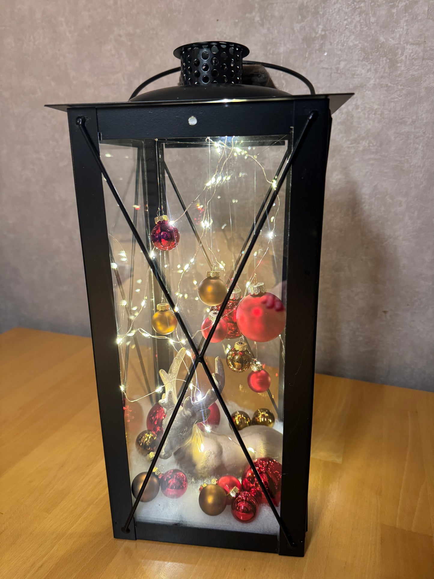 Weihnachtslaterne mit Hirsch – handgemachtes Unikat aus Metall und Glas, gefüllt mit winterlicher Dekoration.