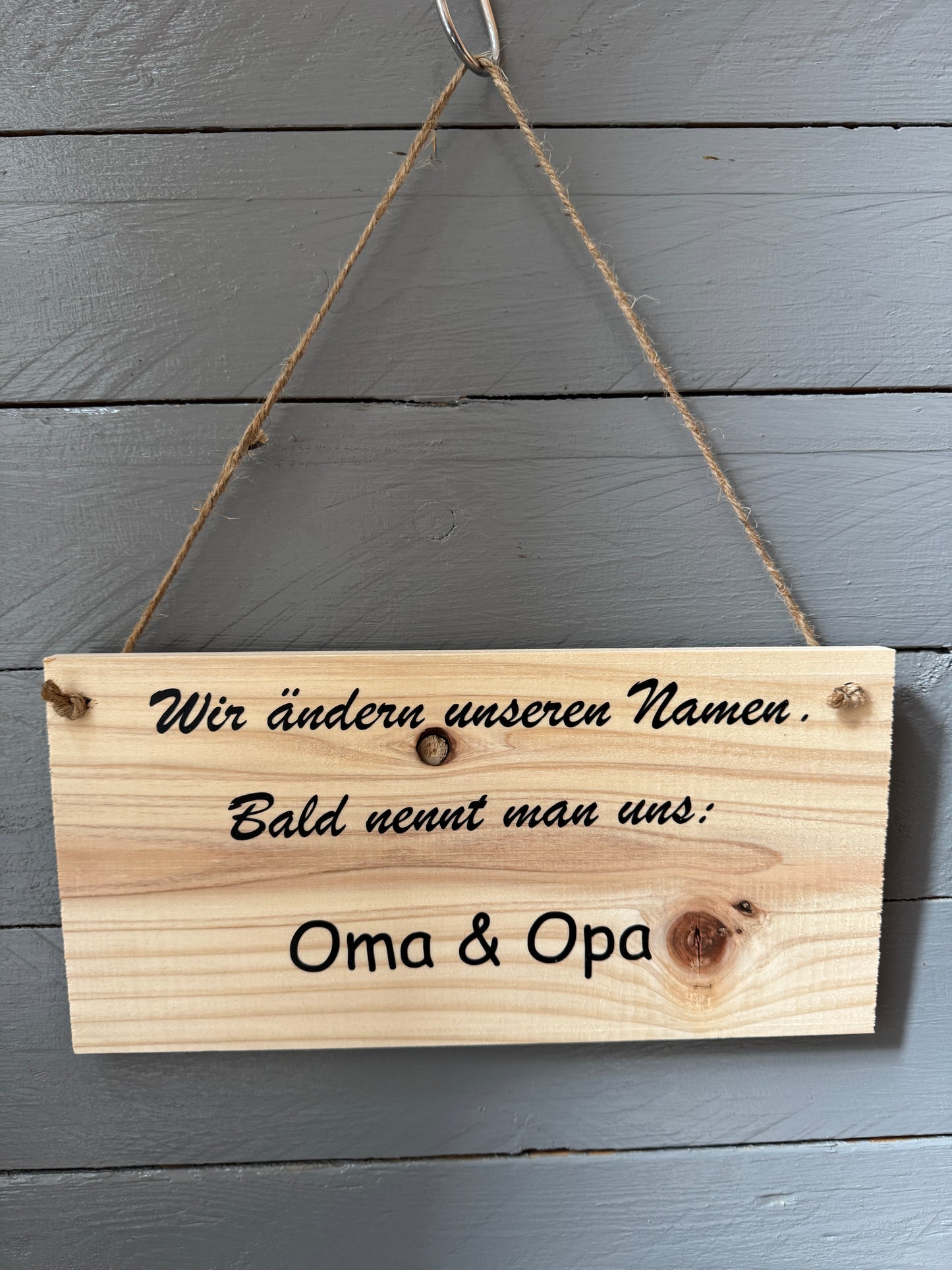 Holzschild mit Spruch „Wir ändern unseren Namen – Man nennt uns Oma & Opa“, handgefertigt, aufgehängt an Wand, liebevolle Geschenkidee für werdende Großeltern