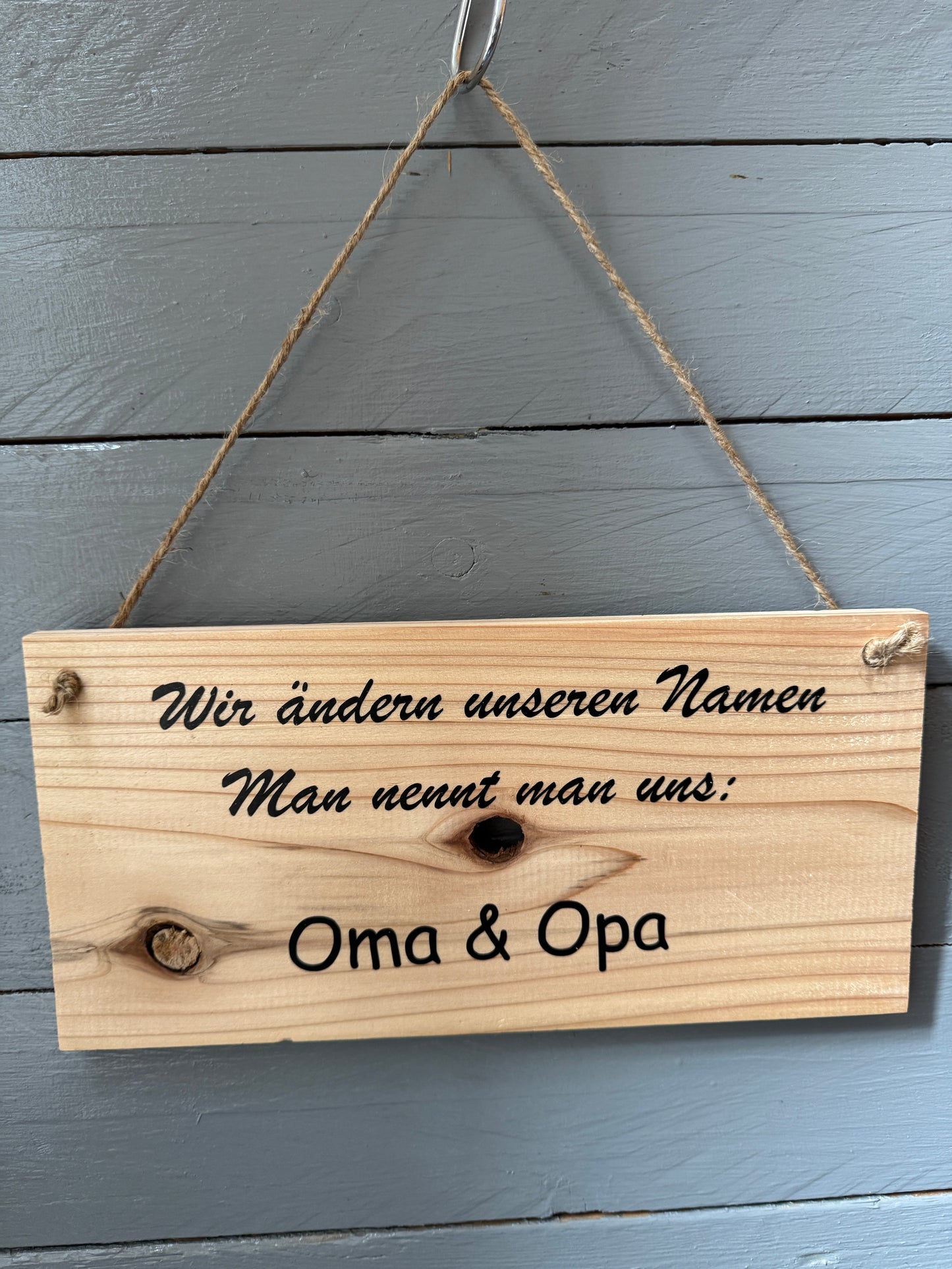 Holzschild mit Spruch „Wir ändern unseren Namen – Man nennt uns Oma & Opa“, handgefertigt, aufgehängt an Wand, liebevolle Geschenkidee für werdende Großeltern