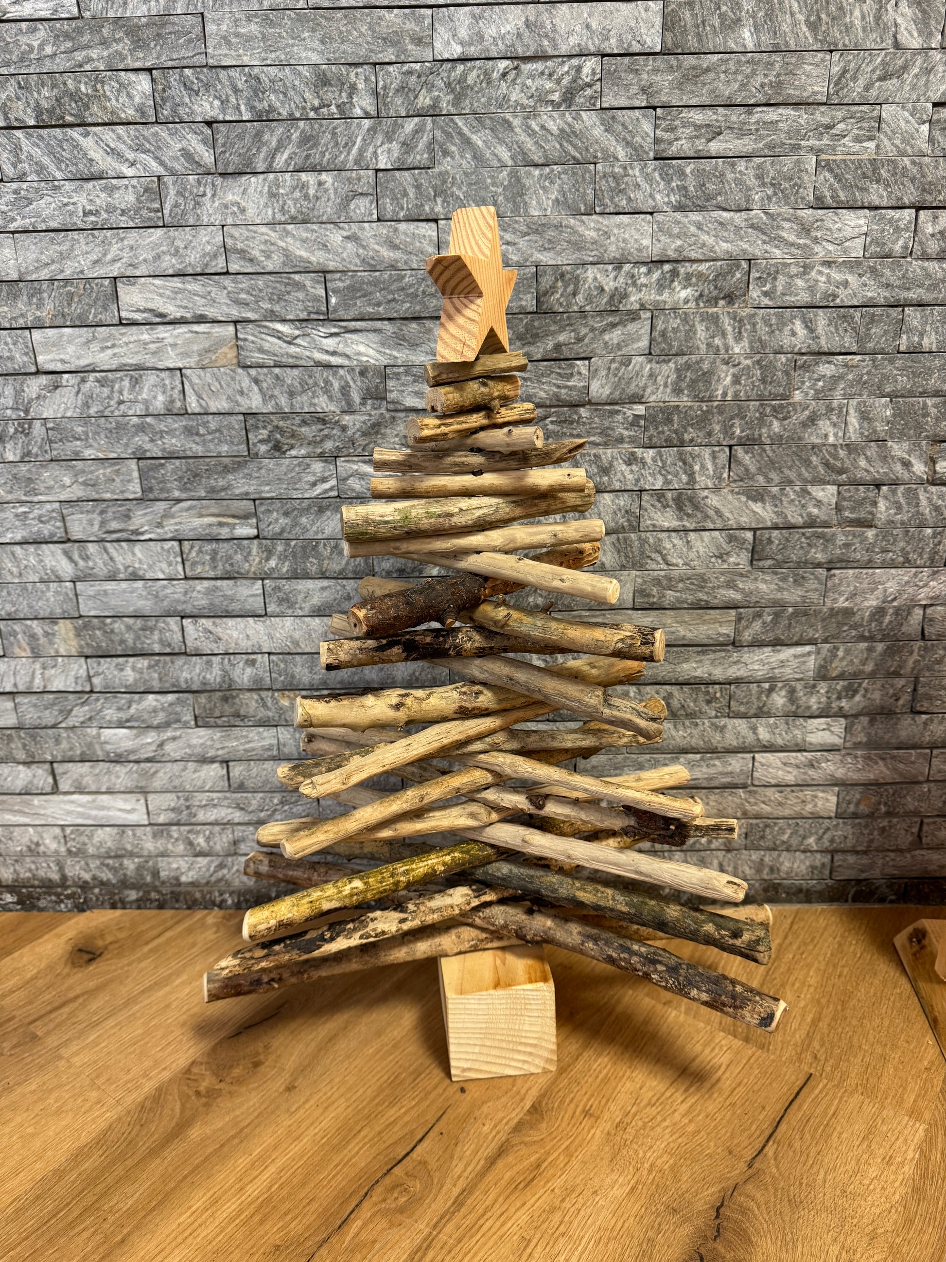 Kleiner Treibholz-Tannenbaum von der Nordsee, liebevoll zusammengesetzt aus vom Meer geformtem Holz, dekorativ auf einem Tisch mit winterlicher Beleuchtung.