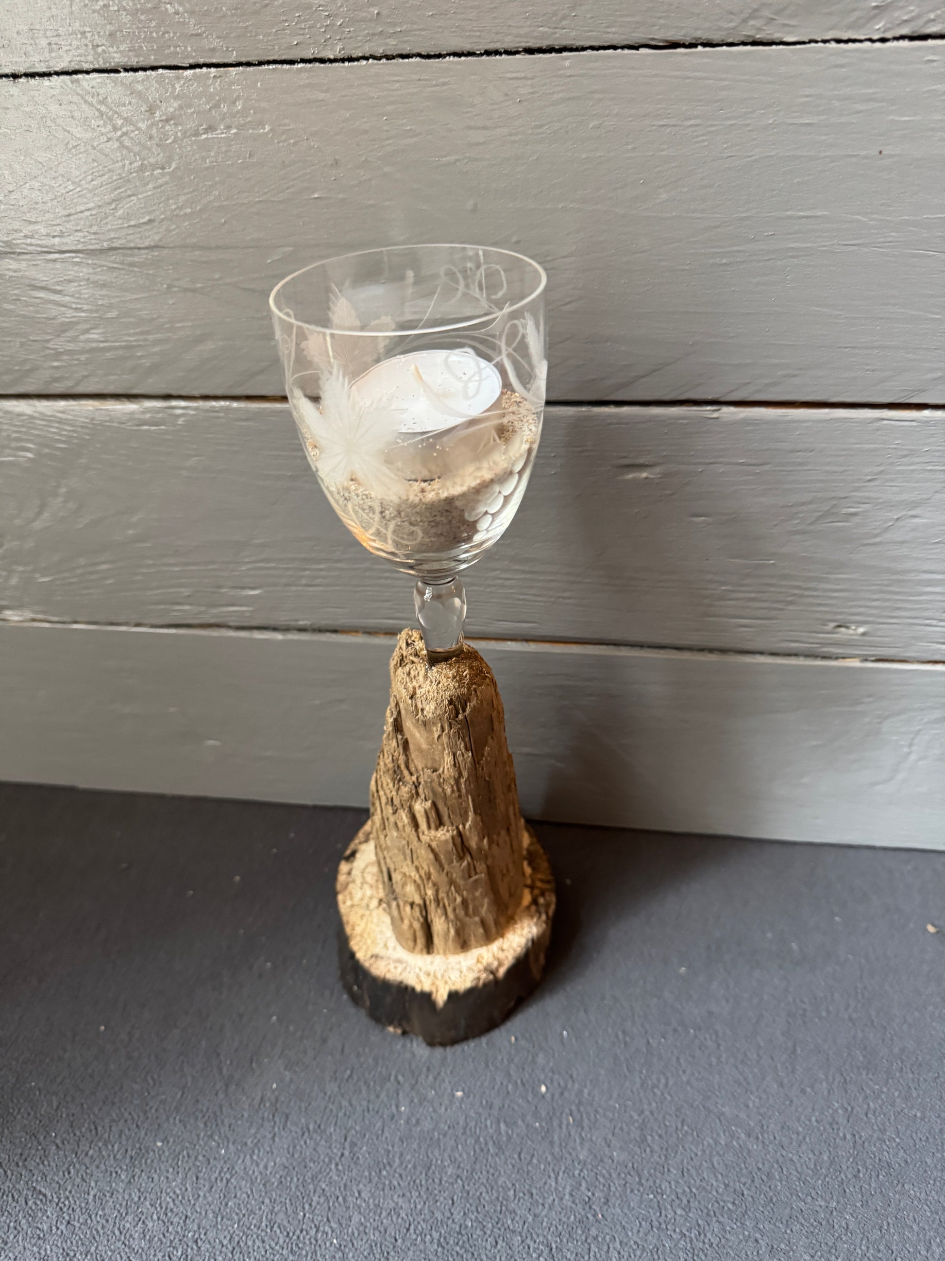 Romantische Teelichtdeko mit Sand und Weinglas auf Holz