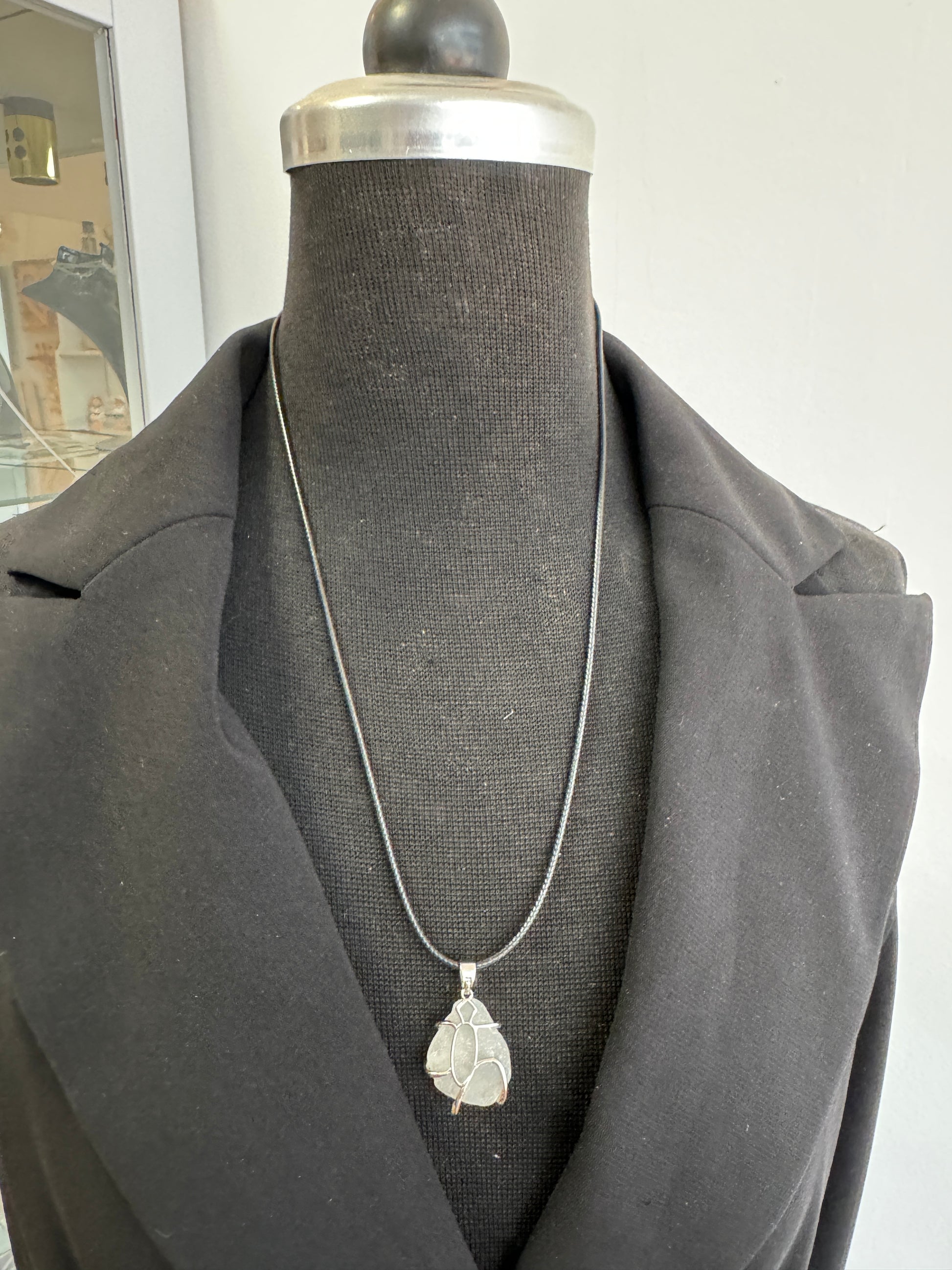 Nahaufnahme vom weißen Anhänger auf schwarzem Band