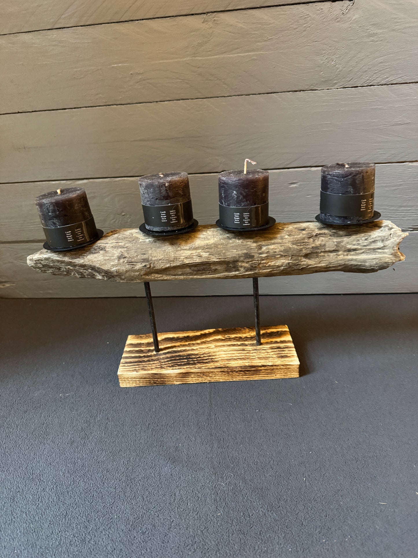 Maritimes Adventsgesteck „Nordlicht“ – schwebendes Treibholz auf gebranntem Holzfuß mit Kerzen in dunklem Grau.