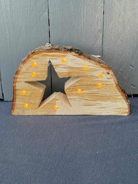 Handgefertigte Baumscheibe aus naturbelassenem Holz mit eingesägtem Stern und integrierter LED-Lichterkette – warmweiß leuchtend.