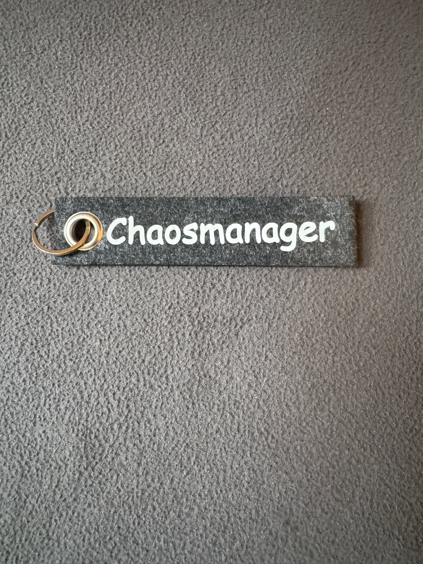 Handgemachter Filzanhänger mit der Aufschrift „Chaosmanager“.