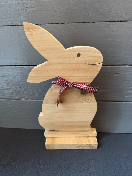 Kleiner handgefertigter Holz-Osterhase mit kariertem Stoffband als rustikale Osterdekoration