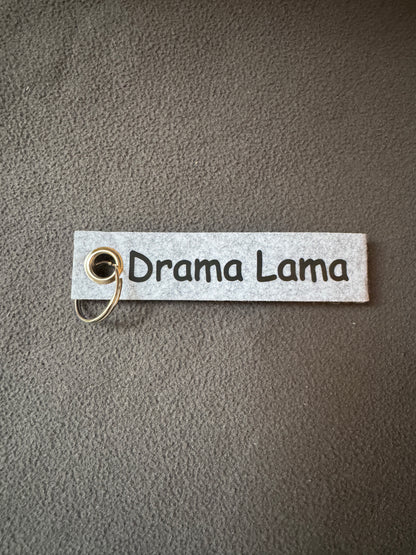 Grauer Filzanhänger mit dem Spruch „Drama Lama“, humorvolle Geschenkidee.