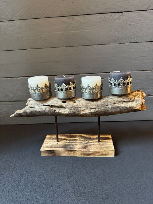 Treibholz-Gesteck „Kronenzauber“ mit vier kleinen Blockkerzen in silbernen Kronenhaltern auf naturbelassenem Treibholz.