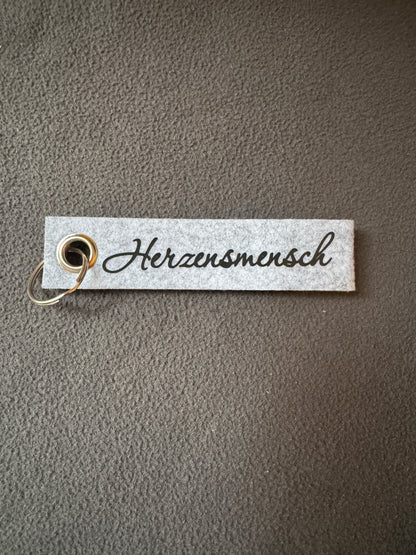 Handgemachter Filz-Schlüsselanhänger mit dem Schriftzug „Herzensmensch“.