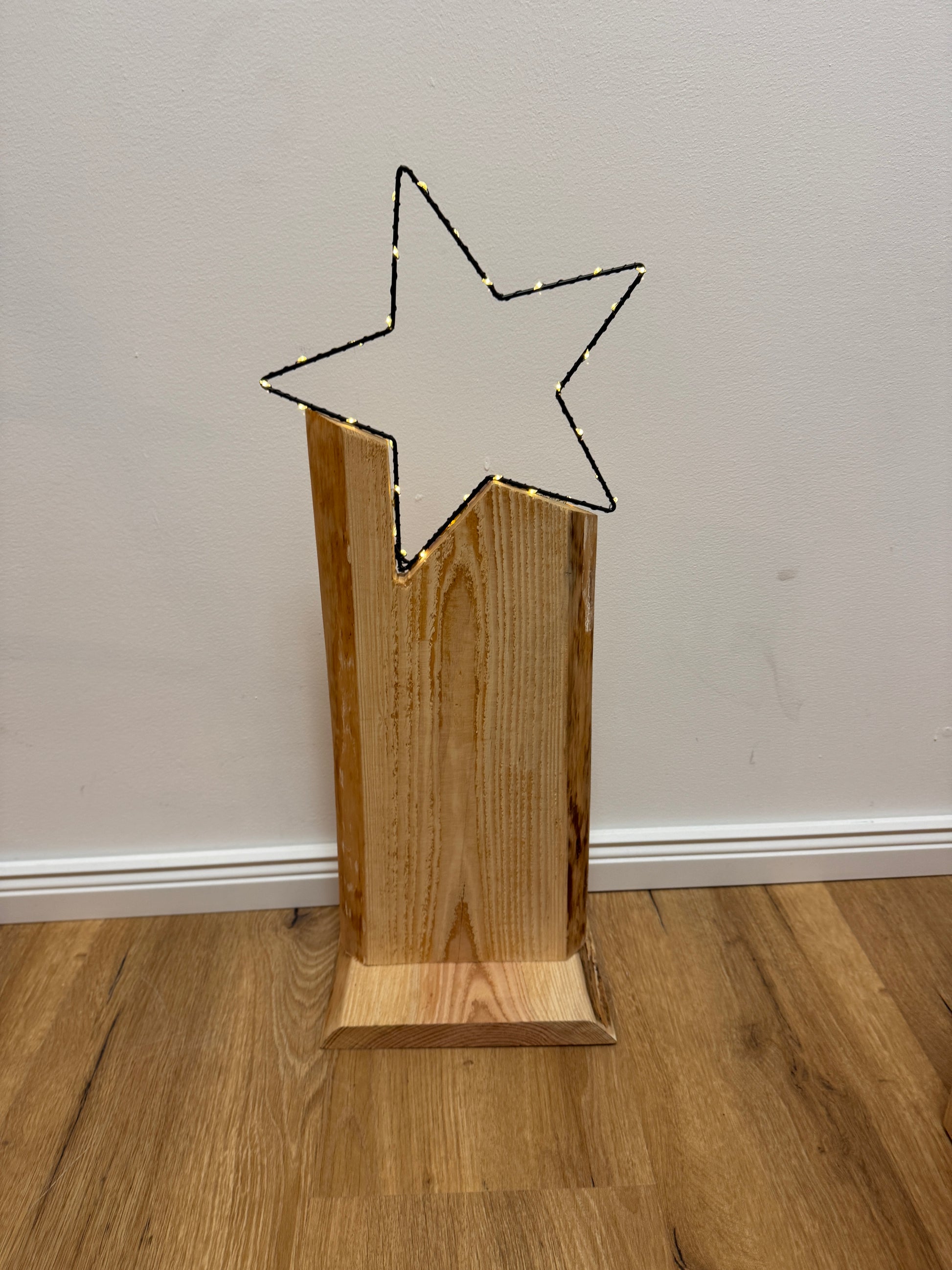 Detailaufnahme LED-Stern auf Holzstele – warmweiße Lichtpunkte auf filigranem Sternrahmen, naturbelassenes Holz.