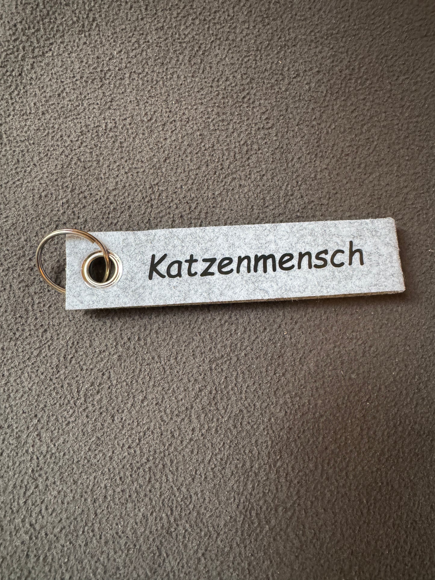 Hellgrauer Filzanhänger mit dem Spruch „Katzenmensch“, nachhaltiges Geschenk.