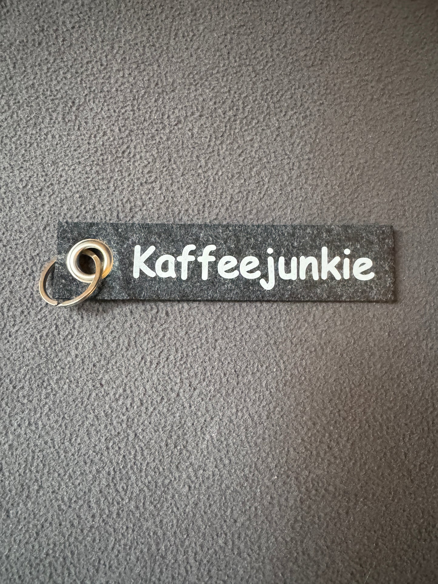 Filzanhänger in Grau mit dem Spruch „Kaffeejunkie“.