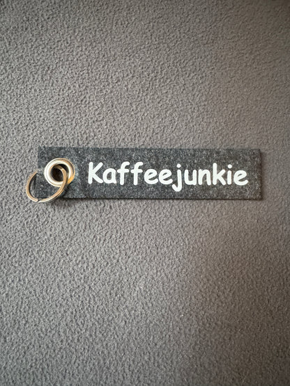 Filzanhänger in Grau mit dem Spruch „Kaffeejunkie“.