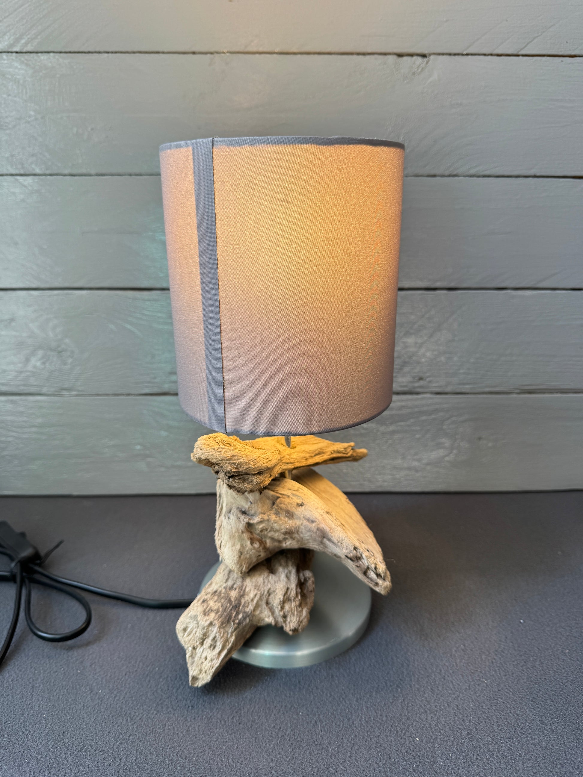 Maritime Tischlampe aus Treibholz mit warmem Licht und modernem Taupe-Schirm.
