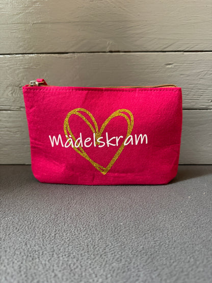 Kosmetiktasche aus Filz in Pink mit goldenem Herz und Schriftzug „Mädelskram“.