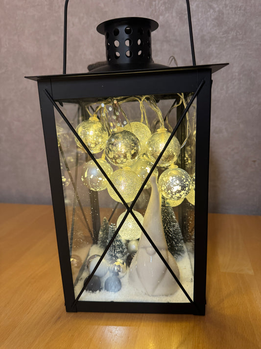 Detailaufnahme der Weihnachtslaterne – Wichtelfigur zwischen Schneelandschaft, Tannenbäumchen und funkelnden Lichterkugeln.