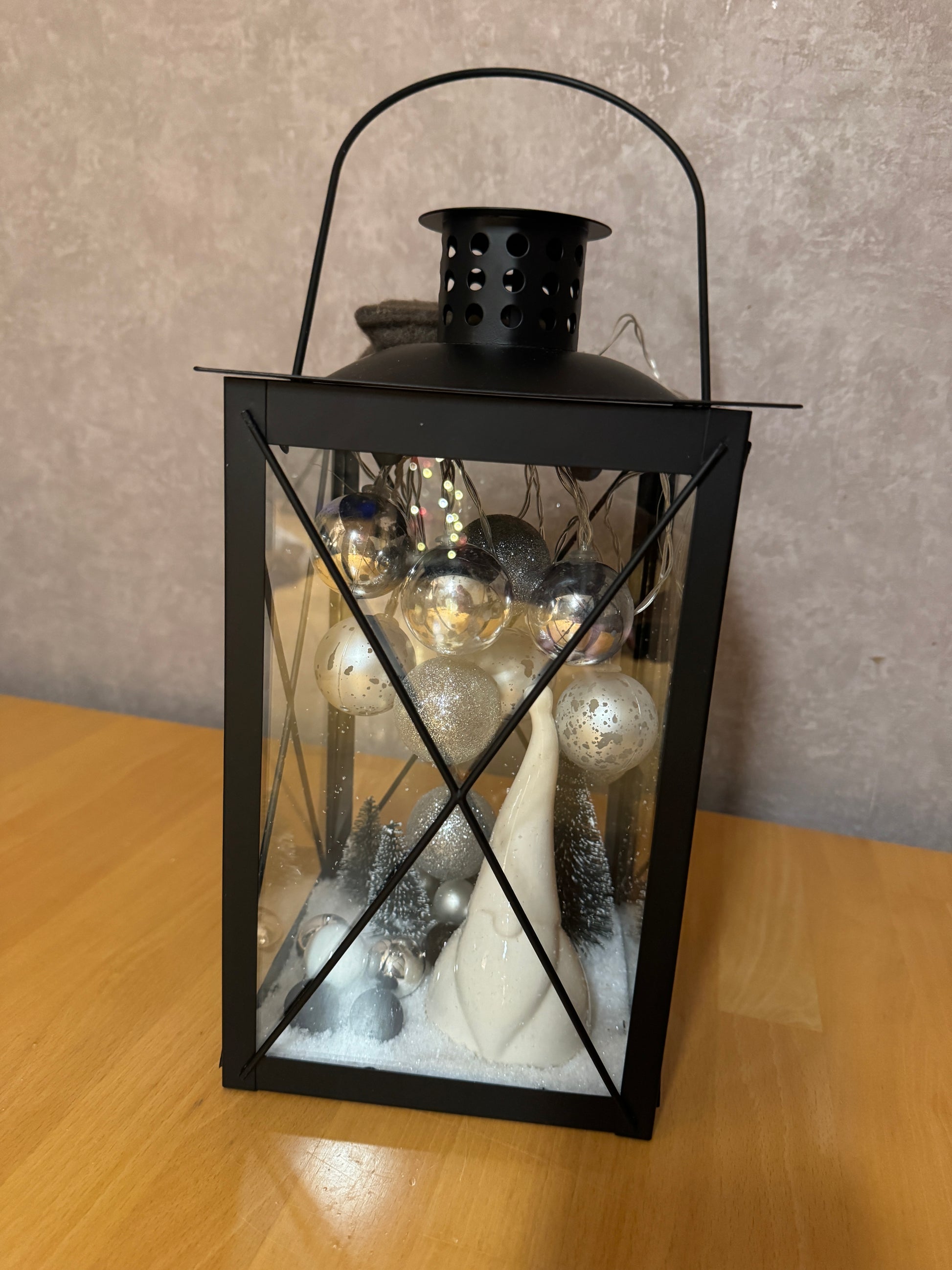 Weihnachtslaterne aus schwarzem Metall mit LED-Lichterkette und winterlicher Dekoration – handgemacht und einzigartig.