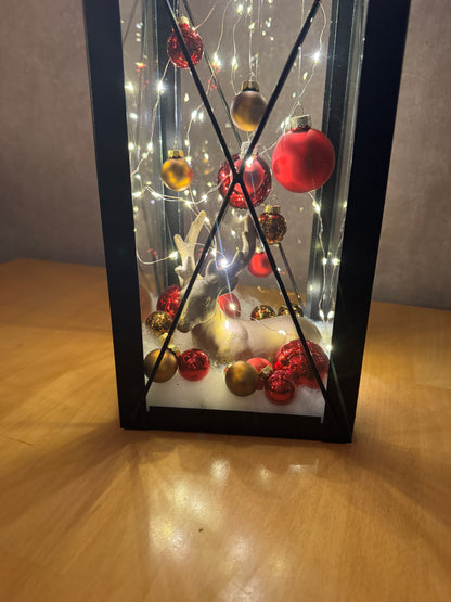Detailaufnahme Weihnachtslaterne – roter & goldener Christbaumschmuck mit Rentierfigur und Lichterglanz.