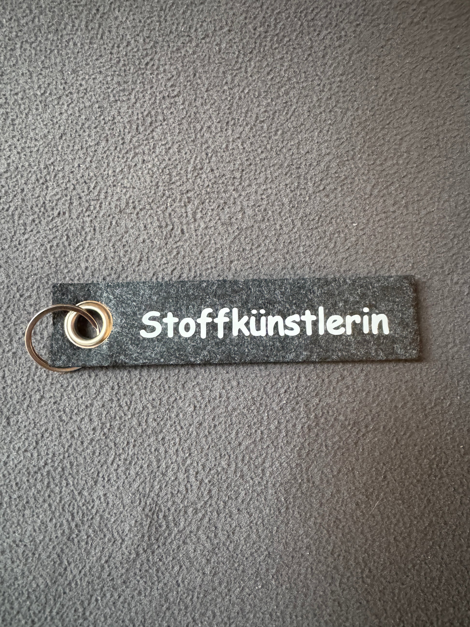 Kleiner Filz-Schlüsselanhänger mit dem Text „Stoffkünstlerin“, ideal für Kreative.