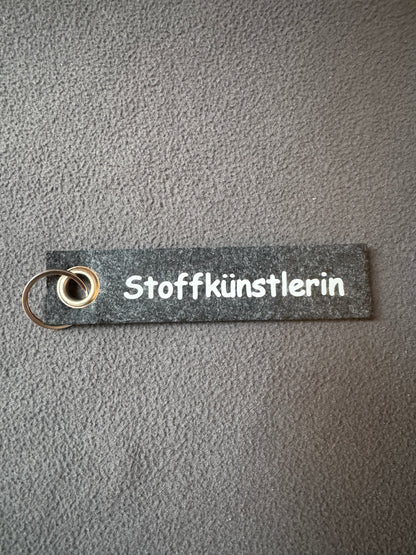 Kleiner Filz-Schlüsselanhänger mit dem Text „Stoffkünstlerin“, ideal für Kreative.
