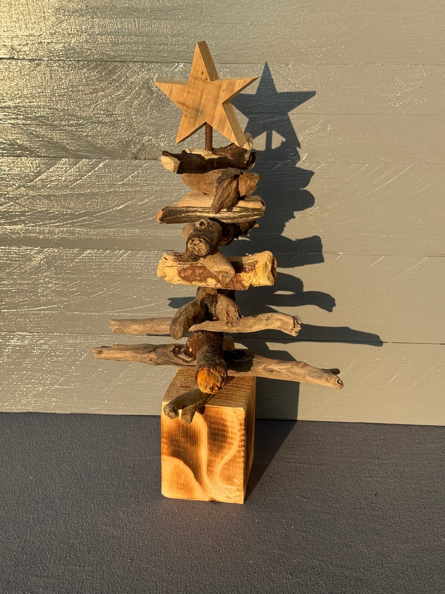 Treibholz-Tannenbaum auf Holzsockel mit natürlicher Maserung und dekorativem Stern – maritimes Unikat als Weihnachtsdeko.