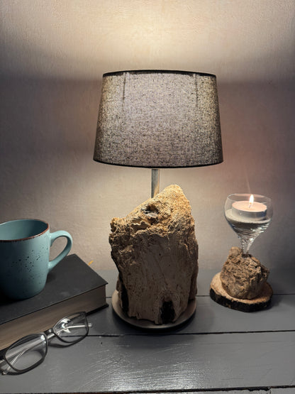 Treibholzlampe mit ovalem grauem Lampenschirm im warmen Licht
