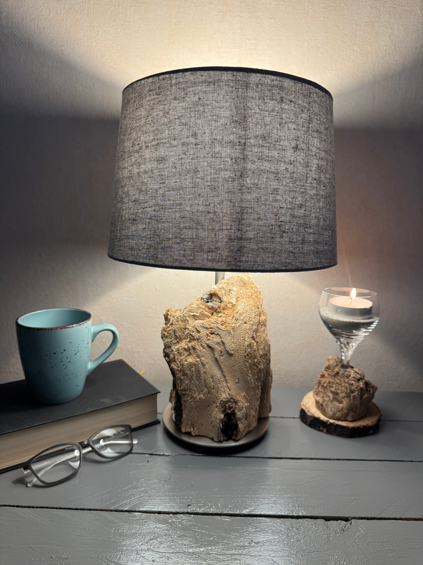 Treibholzlampe mit ovalem grauem Lampenschirm im warmen Licht
