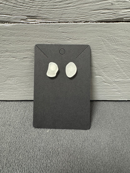 Weiße Meerglas-Ohrringe auf Holz präsentiert – zarte, maritime Schmuckstücke.