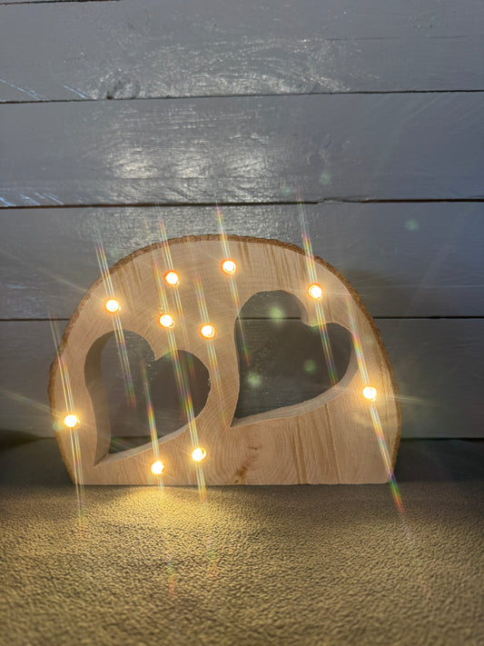 Handgefertigte Baumscheibe mit zwei eingesägten Herzen und LED-Lichterkette aus Schleswig-Holstein leuchtend 