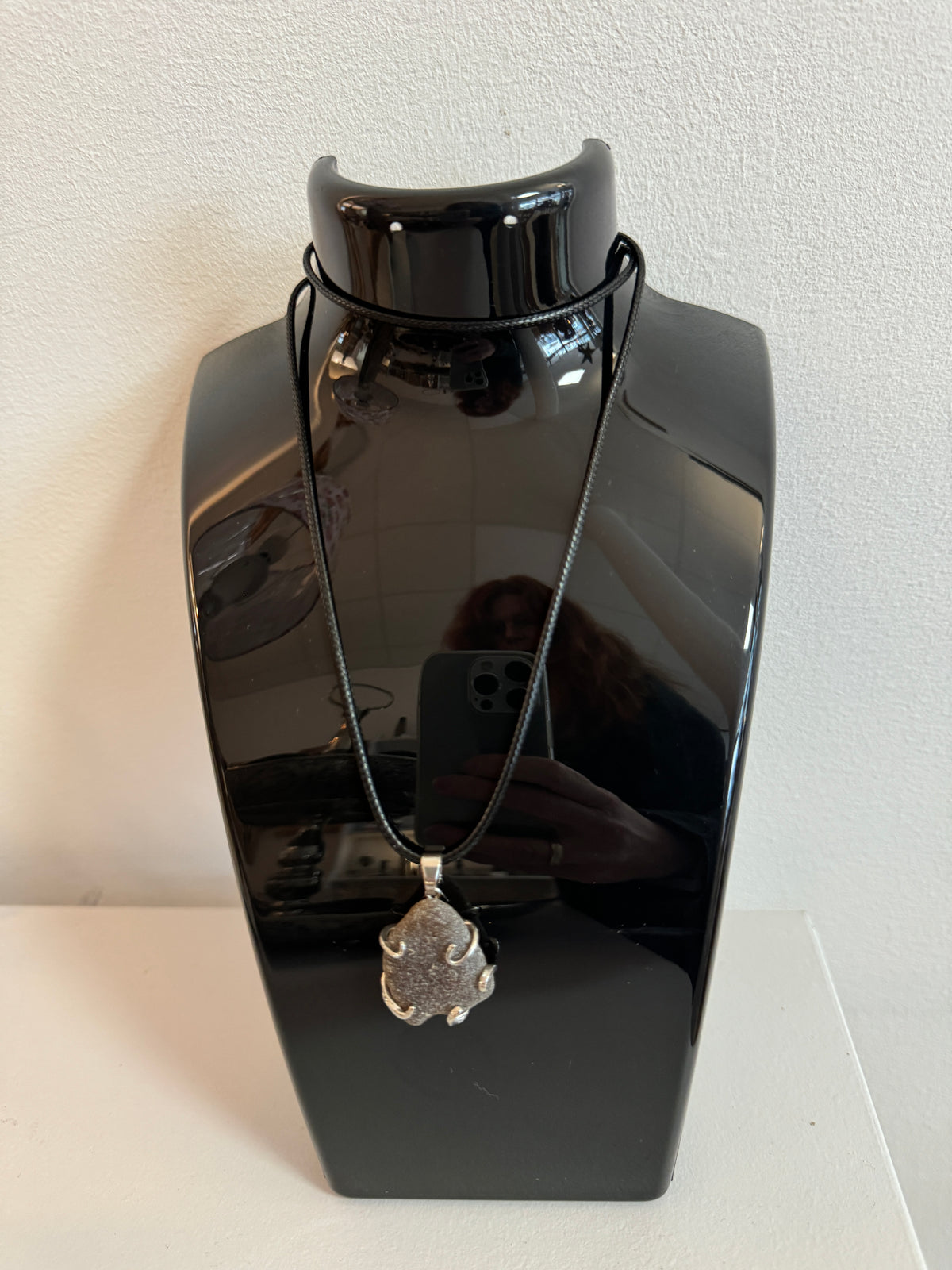 Braune Meerglas-Kette mit silberfarbener Fassung und schwarzem Band auf schwarzer Schmuckbüste