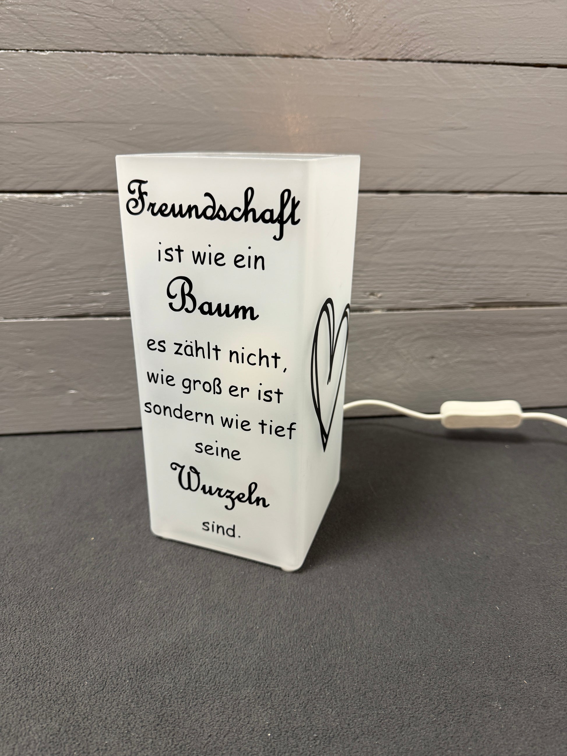 Glaslampe mit Freundschaftsspruch über Baum und Wurzeln