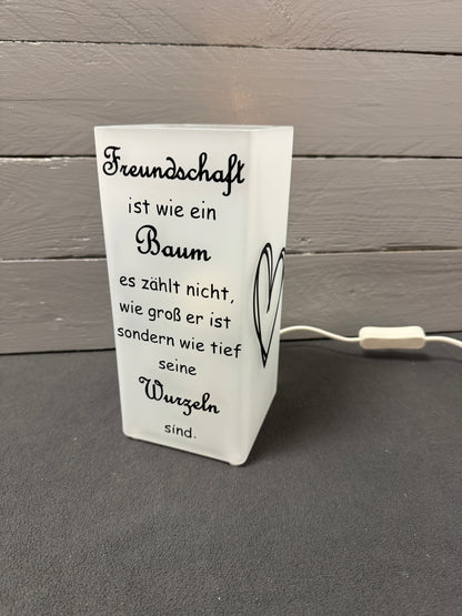 Glaslampe mit Freundschaftsspruch über Baum und Wurzeln