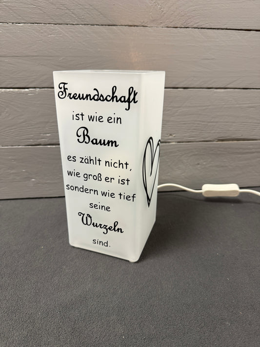 Glaslampe mit Freundschaftsspruch über Baum und Wurzeln