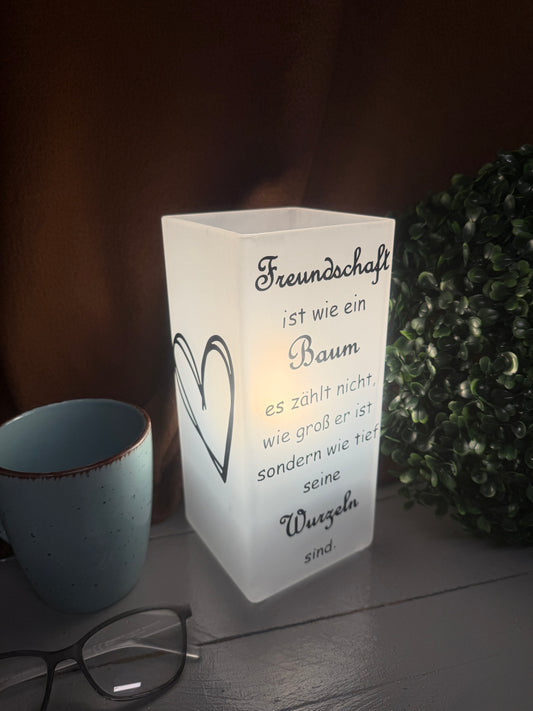 Beleuchtete Glaslampe Freundschaft Tiefe Wurzeln mit warmem Licht.
