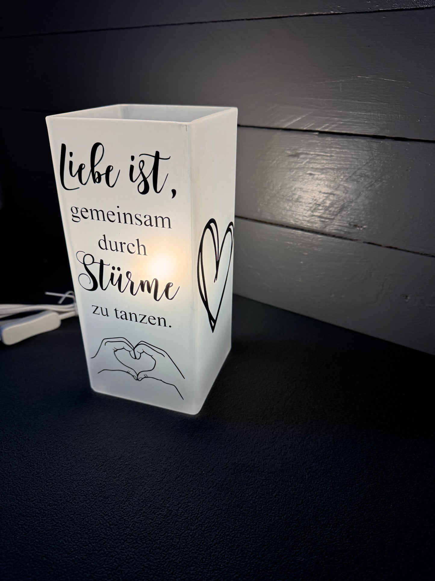 Detailaufnahme des Spruchs „Gemeinsam durch Stürme zu tanzen“ auf Glaslampe