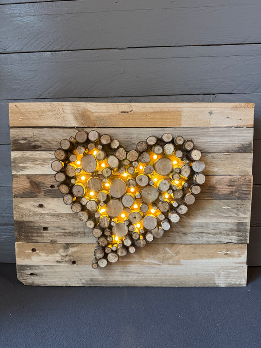 Wandbild mit beleuchtetem Herz aus Astscheiben