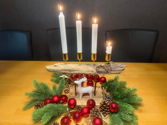 Handgefertigtes Treibholz-Adventsgesteck „Adventsfeuer Goldküste“ mit vier goldenen Stabkerzenhaltern auf geflammtem Holz – weihnachtlich dekoriert und leuchtend.