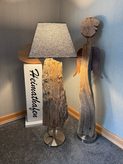 Ansicht der Treibholz-Tischlampe „Ostseelicht Muschelfund“ aus der Region Schwansen mit eckigem Lampenschirm in grau. 