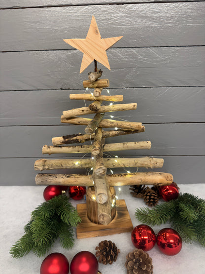 Detailaufnahme des geflammten Altholzfußes und der natürlichen Treibholzäste des handgefertigten Weihnachtsbaums.